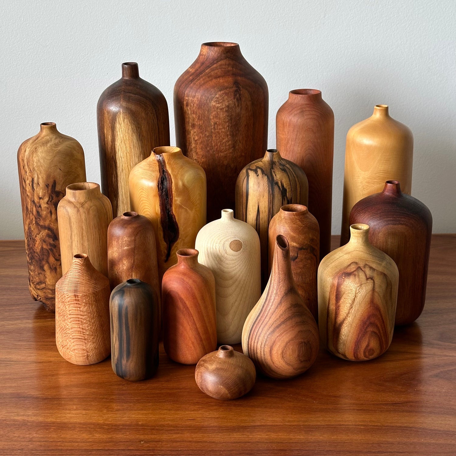 Collection of wooden vases in various shapes and sizes on a wooden surface.